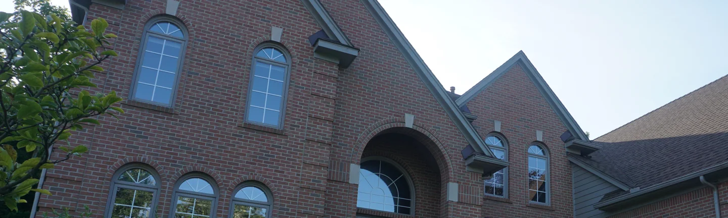 The front gables of a two-story brick house in Novi, Michigan in 2019, the brick reading as one red and tan range across both of them