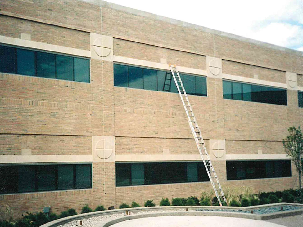 The courtyard wall of the hospital in 1998 with a ladder up to the second floor, the brick a pale buff over both window courses