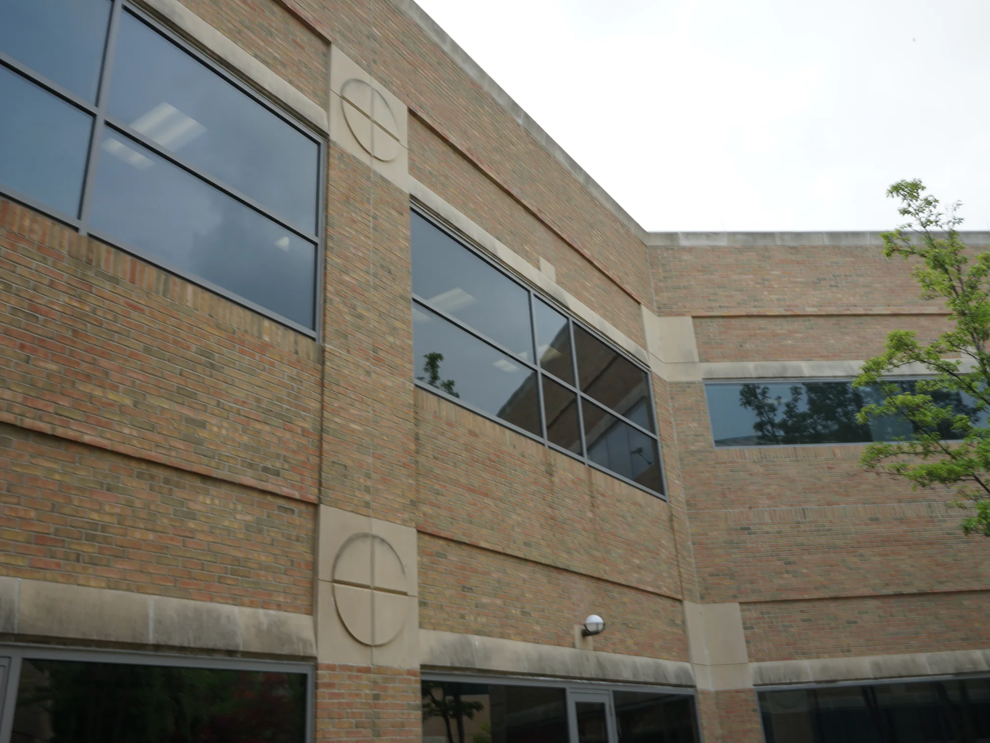 Two wings of the hospital meeting at the courtyard in 2019, the brick reading as one tan and red range across both floors and around the return