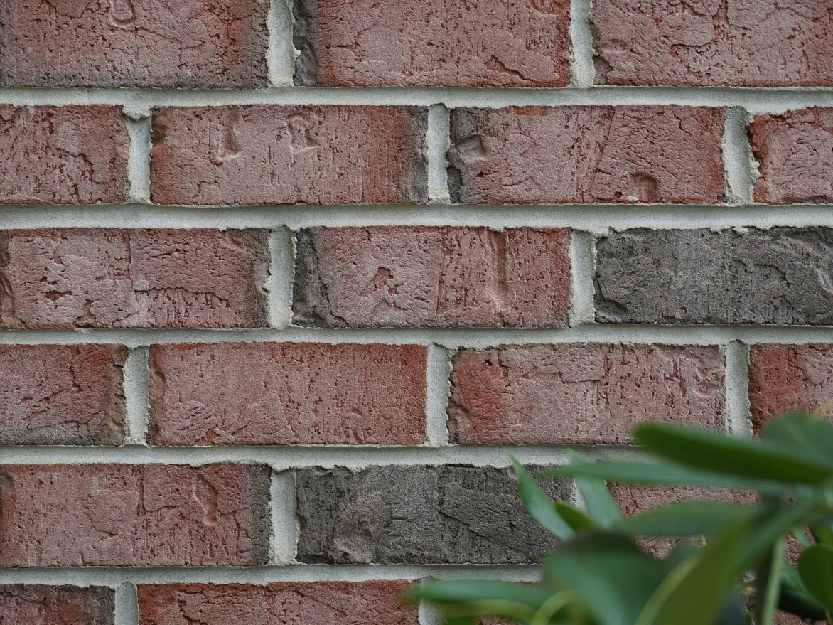 Close view of the brick in 2019, red and tan units with darker headers among them and pale mortar joints