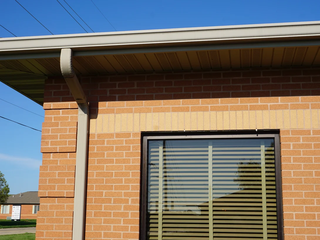 Close view of the soldier band above a window head in 2019, the upright buff units holding one range against the orange brick laid around them