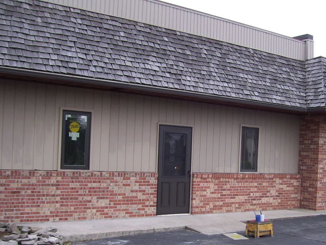 The same side of the clinic later on 08/26/2009, the lower brick one red blend from the left end past the door to the corner pier, a bucket and a stool left on the sidewalk