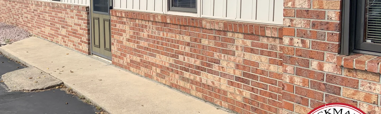 The side wall of the animal clinic in 2019, the lower brick one red blend under the siding from the door to the corner pier