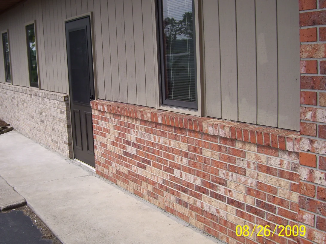 The side wall of the clinic in 2009 before staining, the lower brick to the left of the door a pale buff and the brick right of the door a red blend, with a camera date of 08/26/2009 burned in