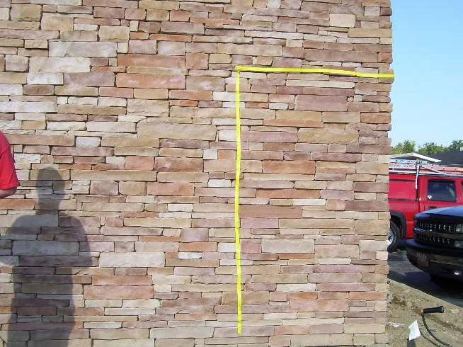 A test area marked out on the untouched wall in 2009 with yellow tape, the stone inside and outside the tape the same pale cream and tan