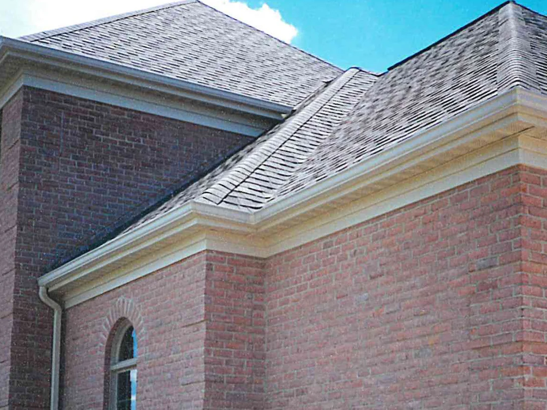 An outside corner of the house in 1997 under its hipped roof and cream eaves, the brick reading as blotchy pink and mauve across both faces