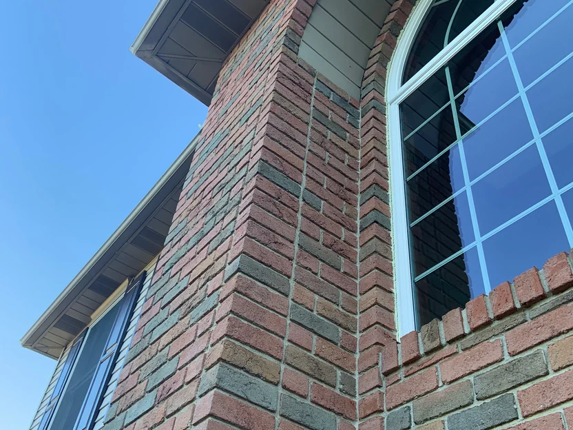 An outside corner of the brick bay in 2019 seen from below, running up to the eaves beside the arched window