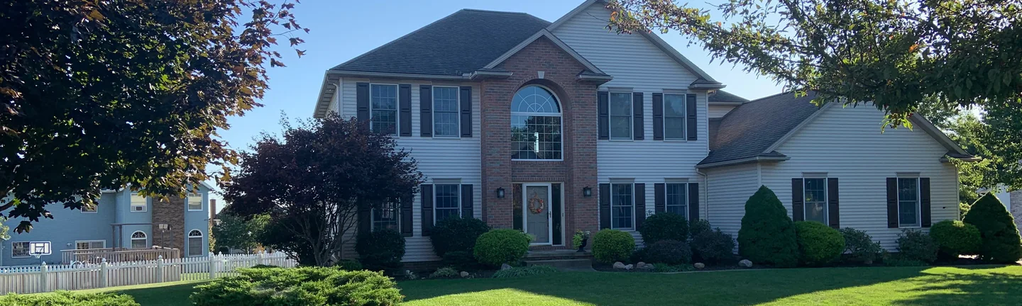 The house from the sidewalk in 2019, its brick centre bay reading as one even blend beside white siding
