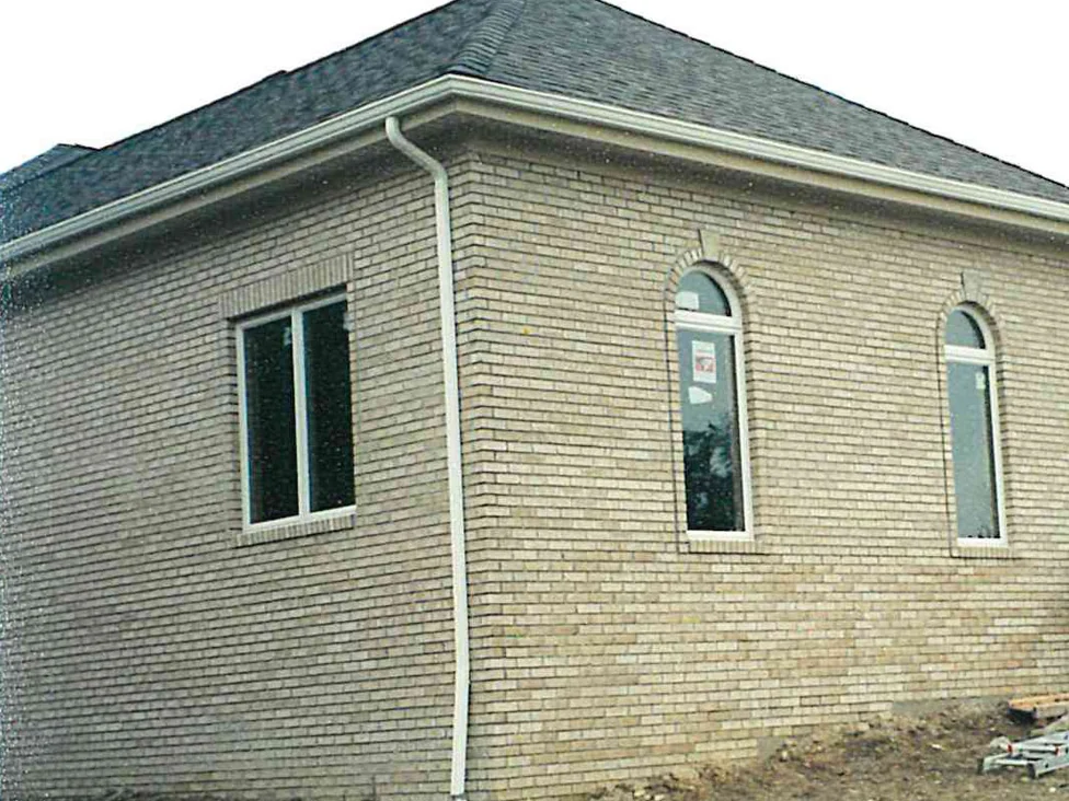 The corner of the house in 2001 with the work under way, three tall arched windows set under radiating brick arches along the end wall and the cream brick around them reading unevenly light and dark