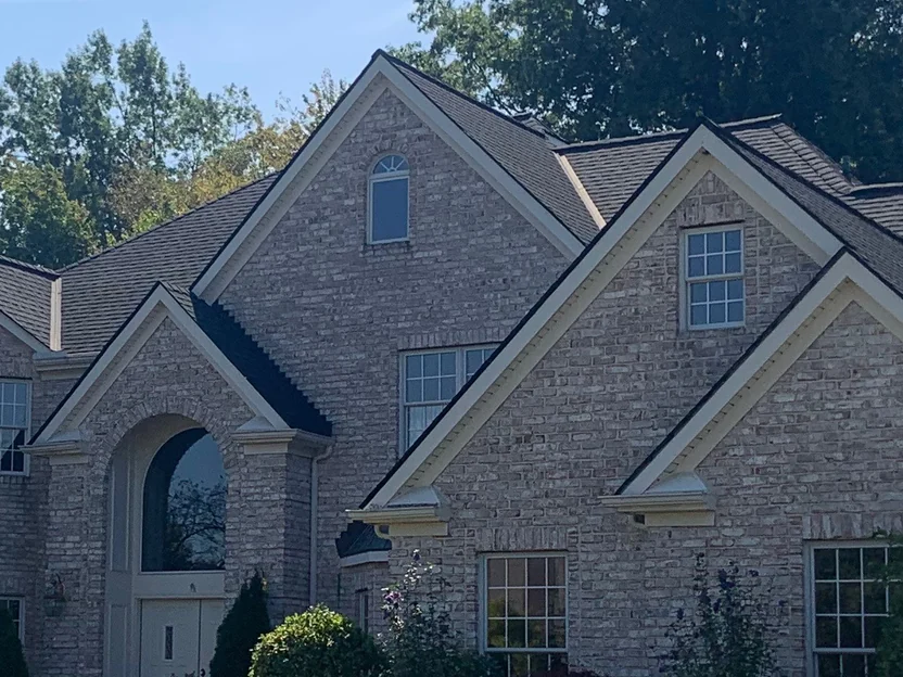 The arched entrance and the two front gables in 2019, the arched window in the gable head and the wall below it holding one cream and tan range
