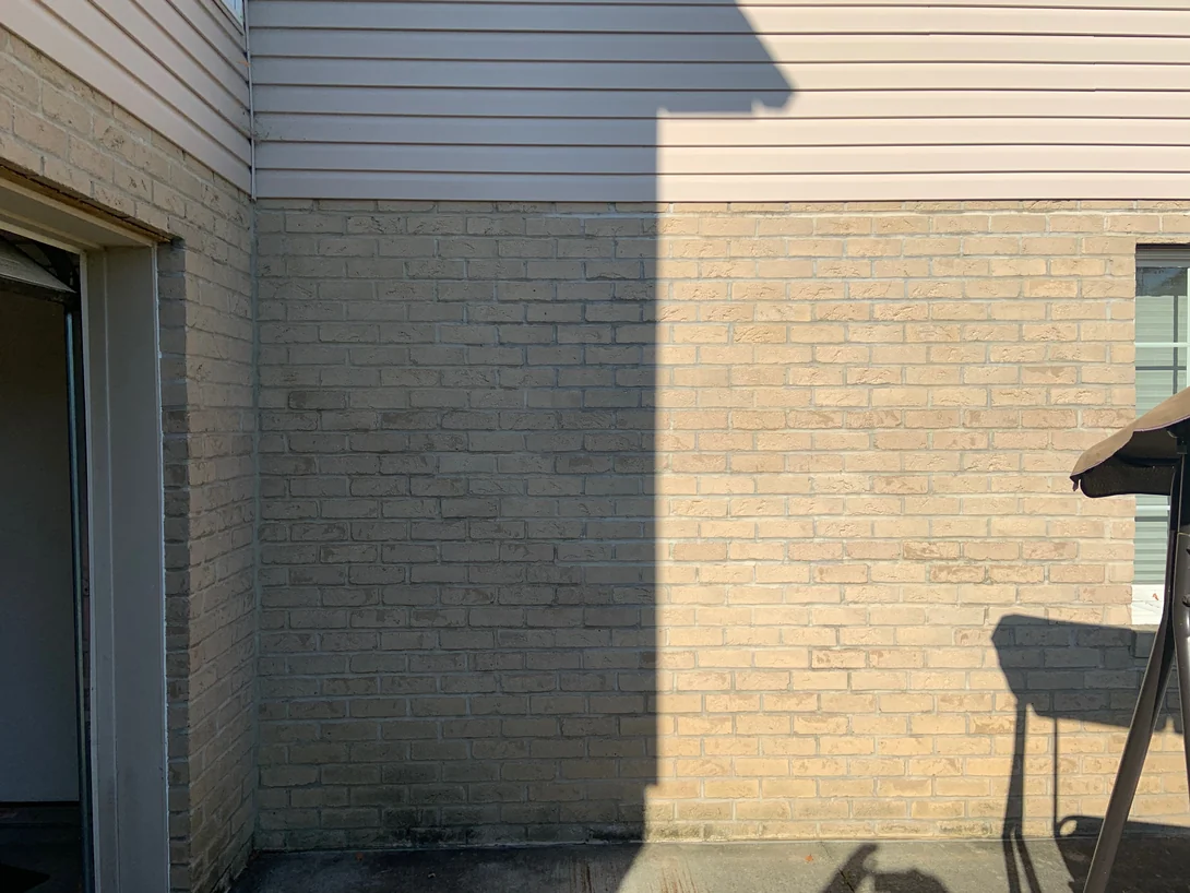 The same patio corner in 2019 with a shadow line falling across it, the brick reading as the same range in sun and in shade