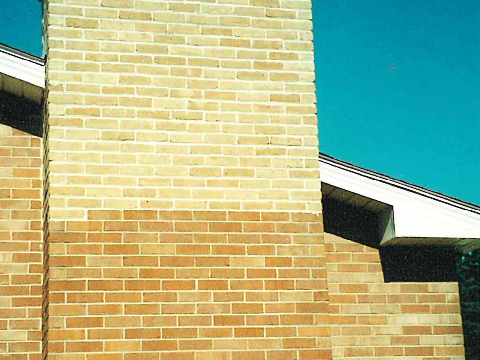 The chimney rising past the roofline in 2001, the brick above the roof a pale cream against the warmer tan and orange brick of the house wall below and beside it