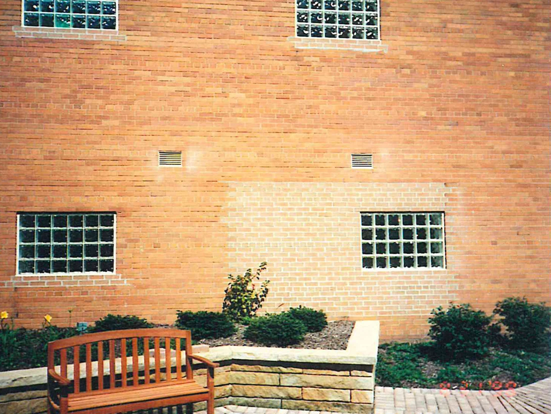 A courtyard wall in 1998, a broad panel of pale brick sitting inside the surrounding orange field, with glass block windows and a stone seat wall below
