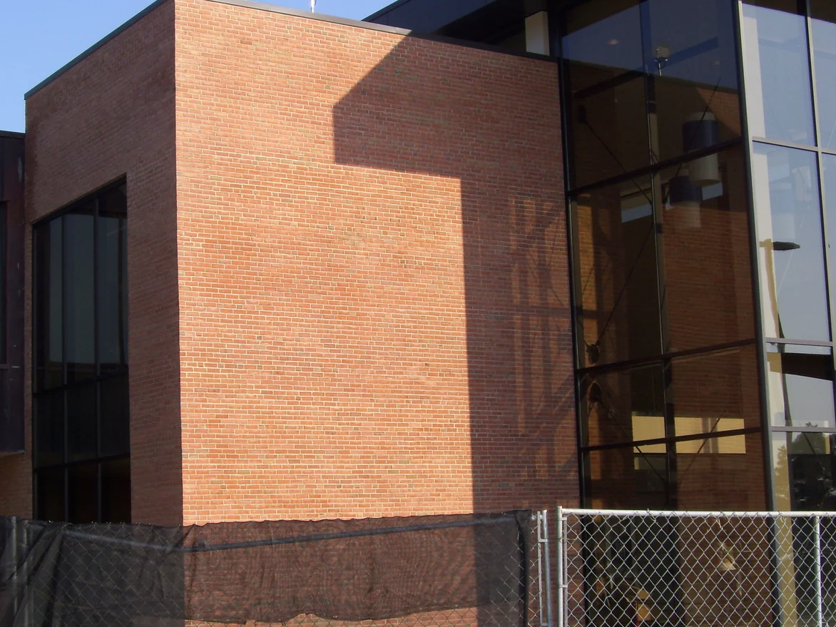 The same brick block from the site fence when the work was finished, the wall holding one red range from the parapet to the ground