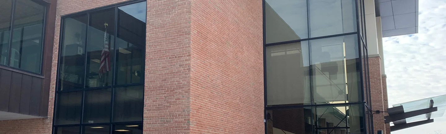 The brick entrance block of the college building, its wall reading as one even red across every course