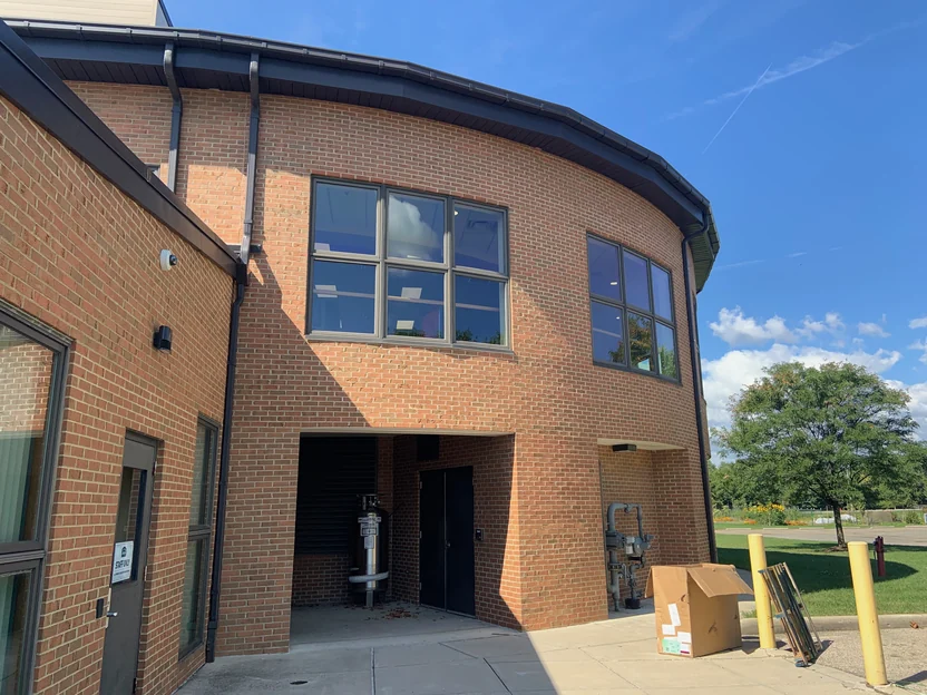 A curved two-storey wing of the same building in 2019, its brick carrying the same range around the bend past two window groups to a service recess