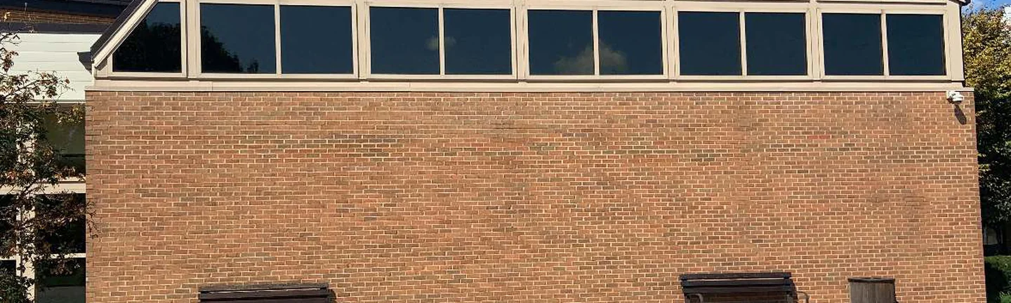 The brick of the Ohio building in 2019, one red brown range running below a wall of dark glazing