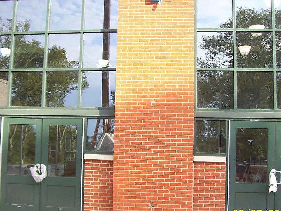 The main entrance of the community center in 2021, both brick piers and the base one even red range around green framed glazing and double doors.
