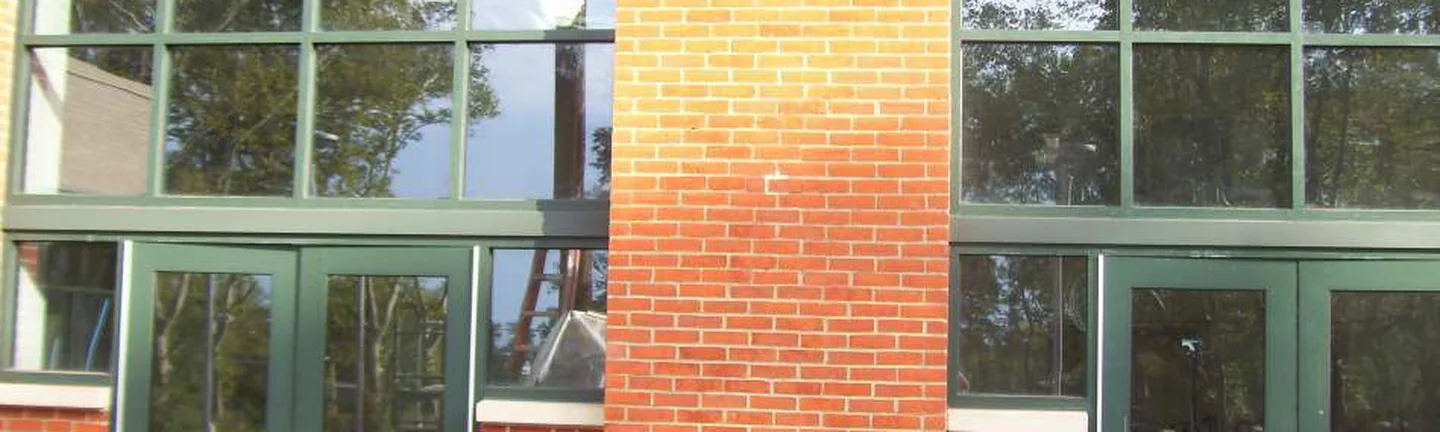 The brick piers and base of the community center entrance in 2021, one even red range around green framed glazing