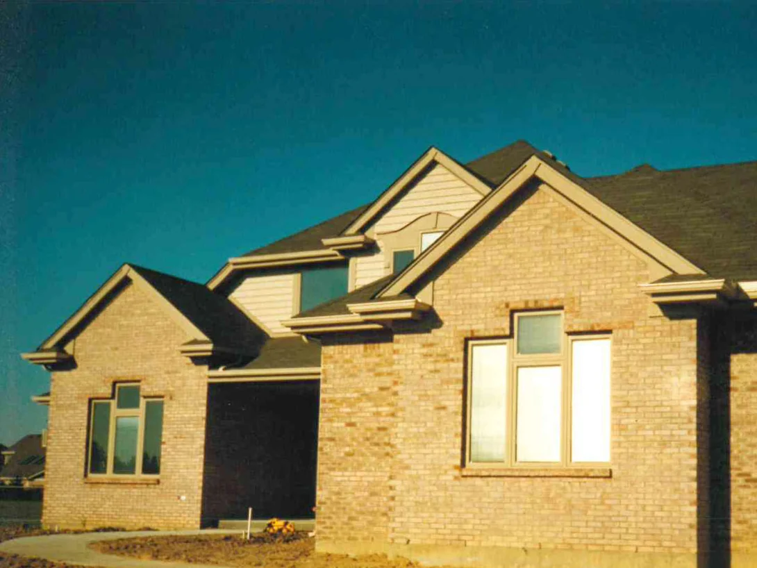 The front corner of the house in 1996, the brick reading as one flat buff tan across the gable end, the garage wall and the wing beyond it