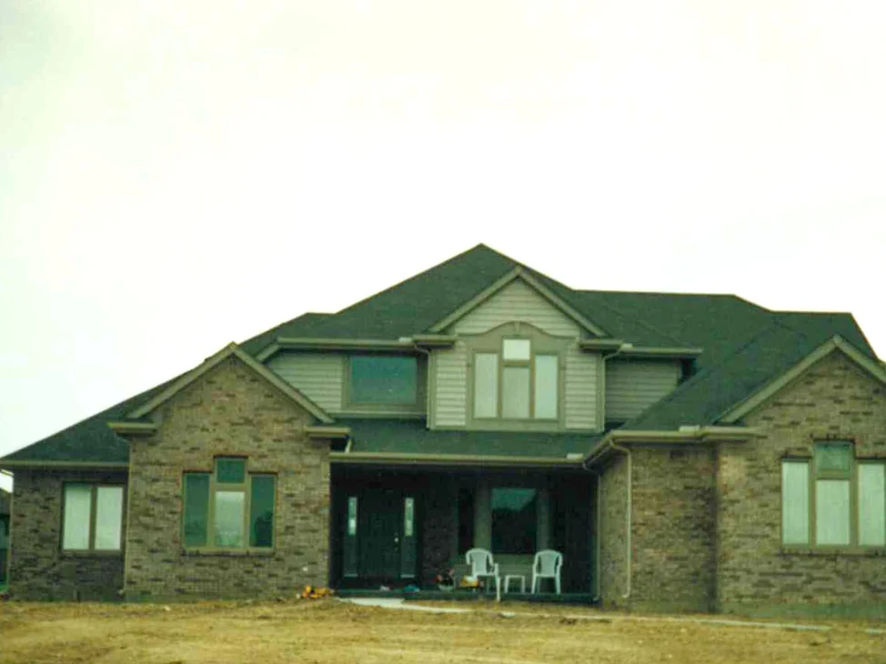 The front of the house in 1996 after the blend, light and dark brick running together across both gable wings and the covered porch between them