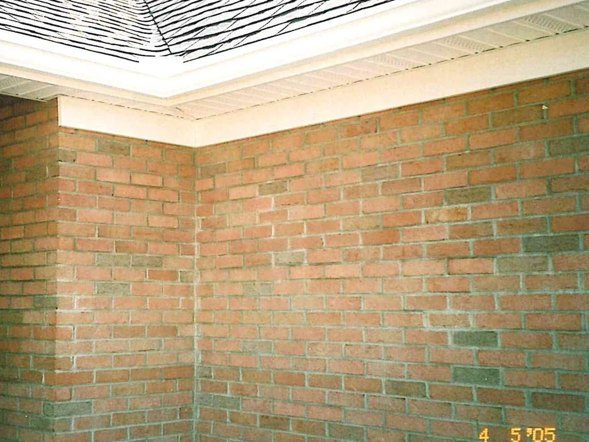 An outside corner of the house in 2005 under a deep white soffit, the brick on both faces reading as one light tan and pink range