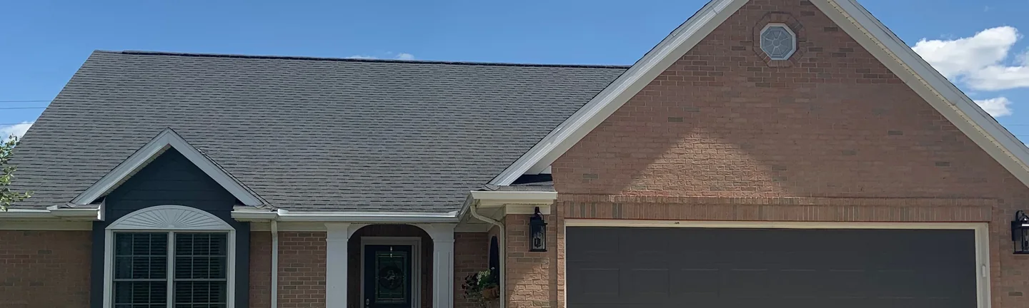 The front of the house in 2019, its brick reading as one light tan and pink range across the garage gable and the entry