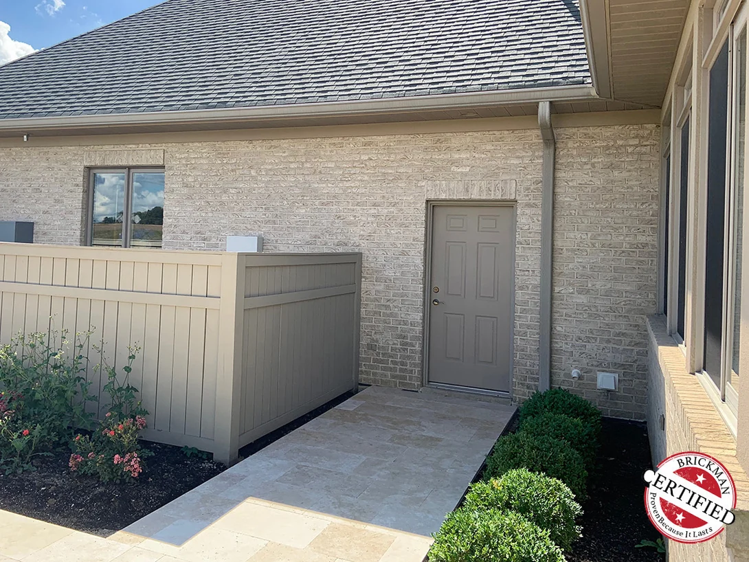 A fenced side courtyard in 2019, the cream brick running from the door surround up to the eaves under the hipped roof