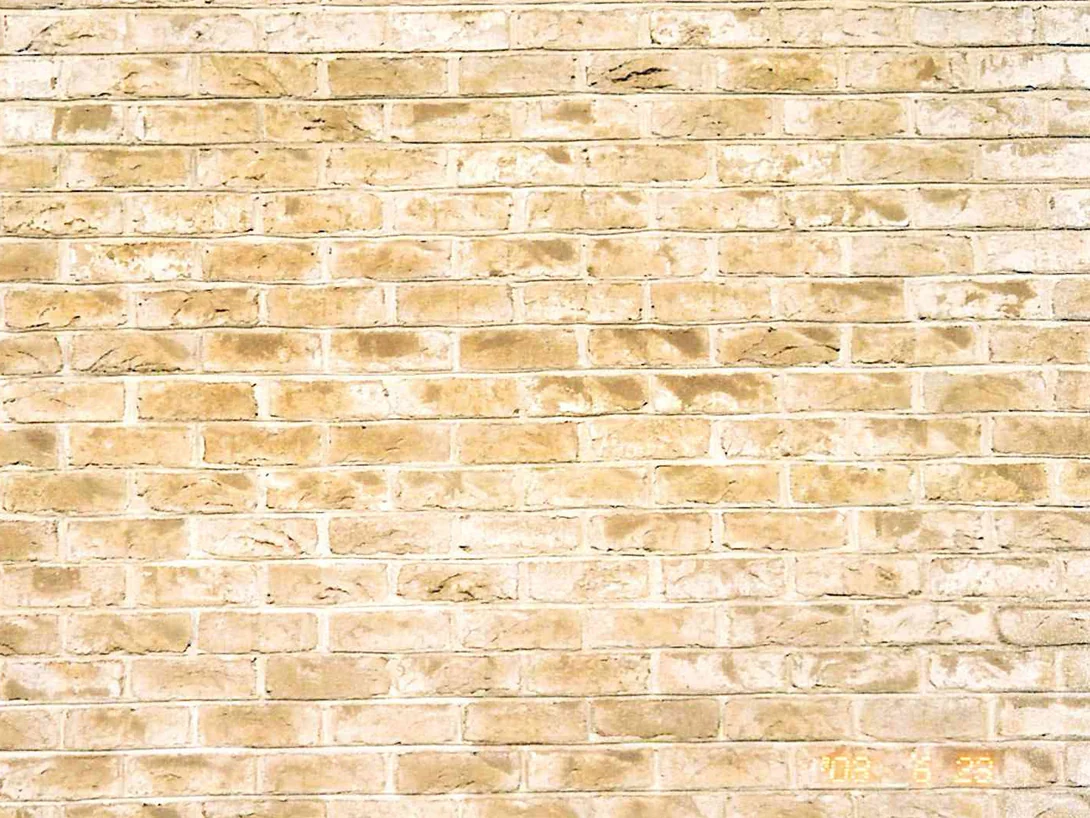 Close view of the wall during the 2003 work, the units a warm cream and tan range with pale joints and a downspout at the left edge