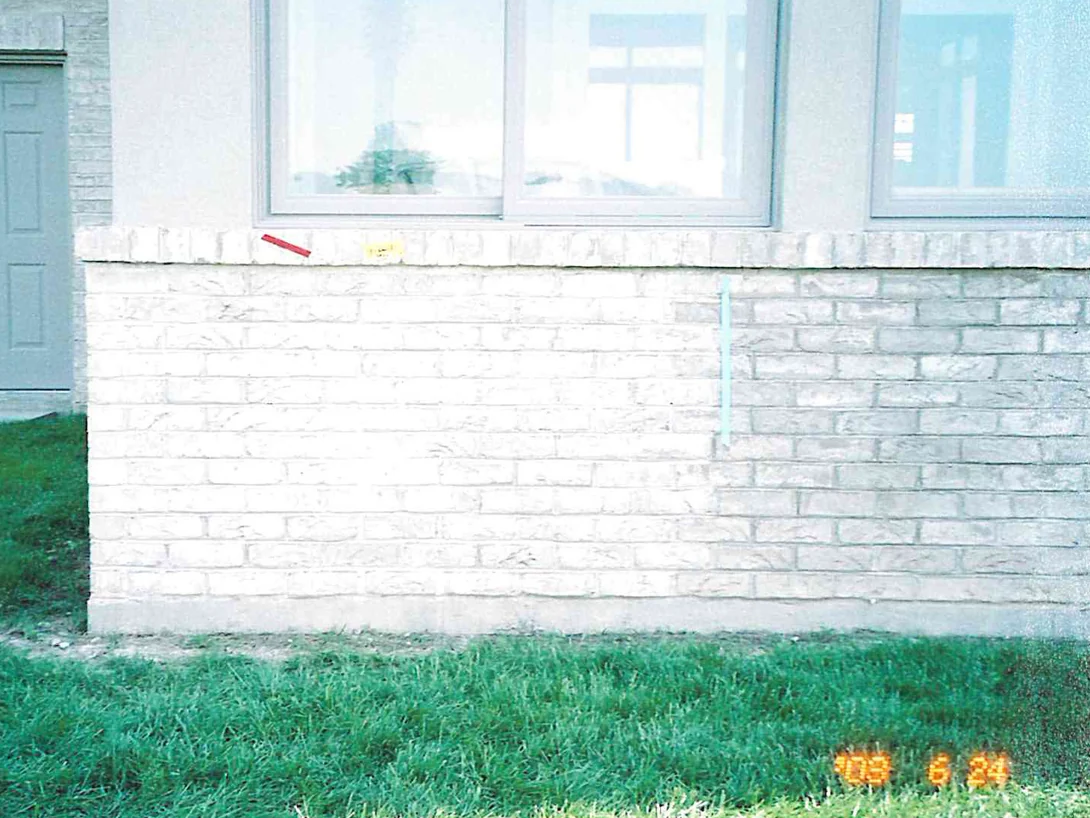 A side entrance and the brick below the windows in 2003, the wall reading as a flat chalky white with faint darker patches