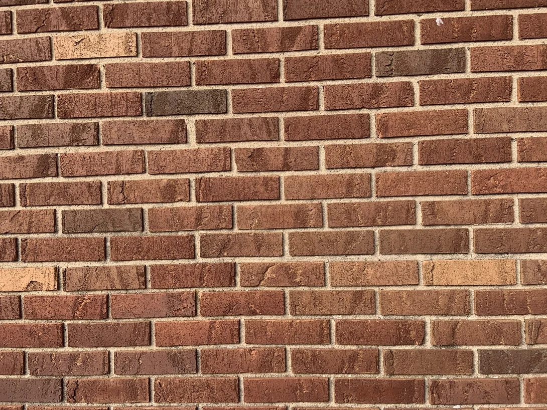 A close view of the brick in 2019, red brown units with a rough wire-cut face and pale grey mortar joints