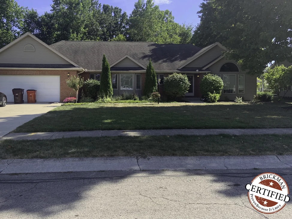 The single-story house from the street in 2019, one range of red brick running across the garage wing and the entry.