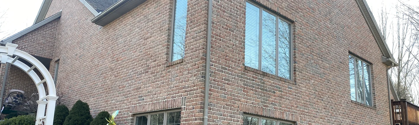 A band of the home's brick in 2021, one even red range running along a side wall to the outside corner under a steep gable