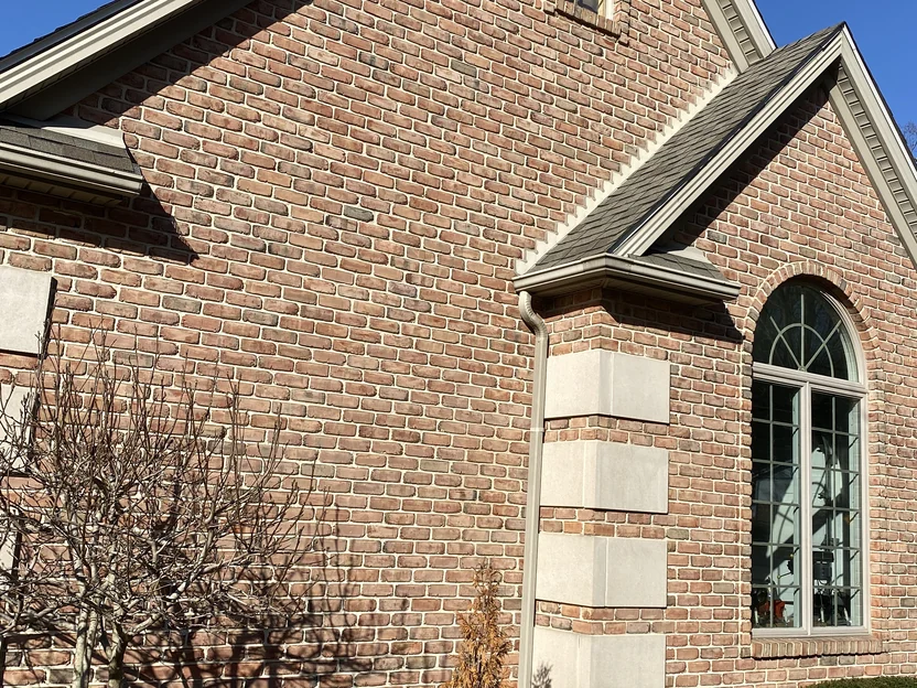 The gable end in 2021, banded limestone quoins at the corner and around the arched window with the brick holding one even range between them