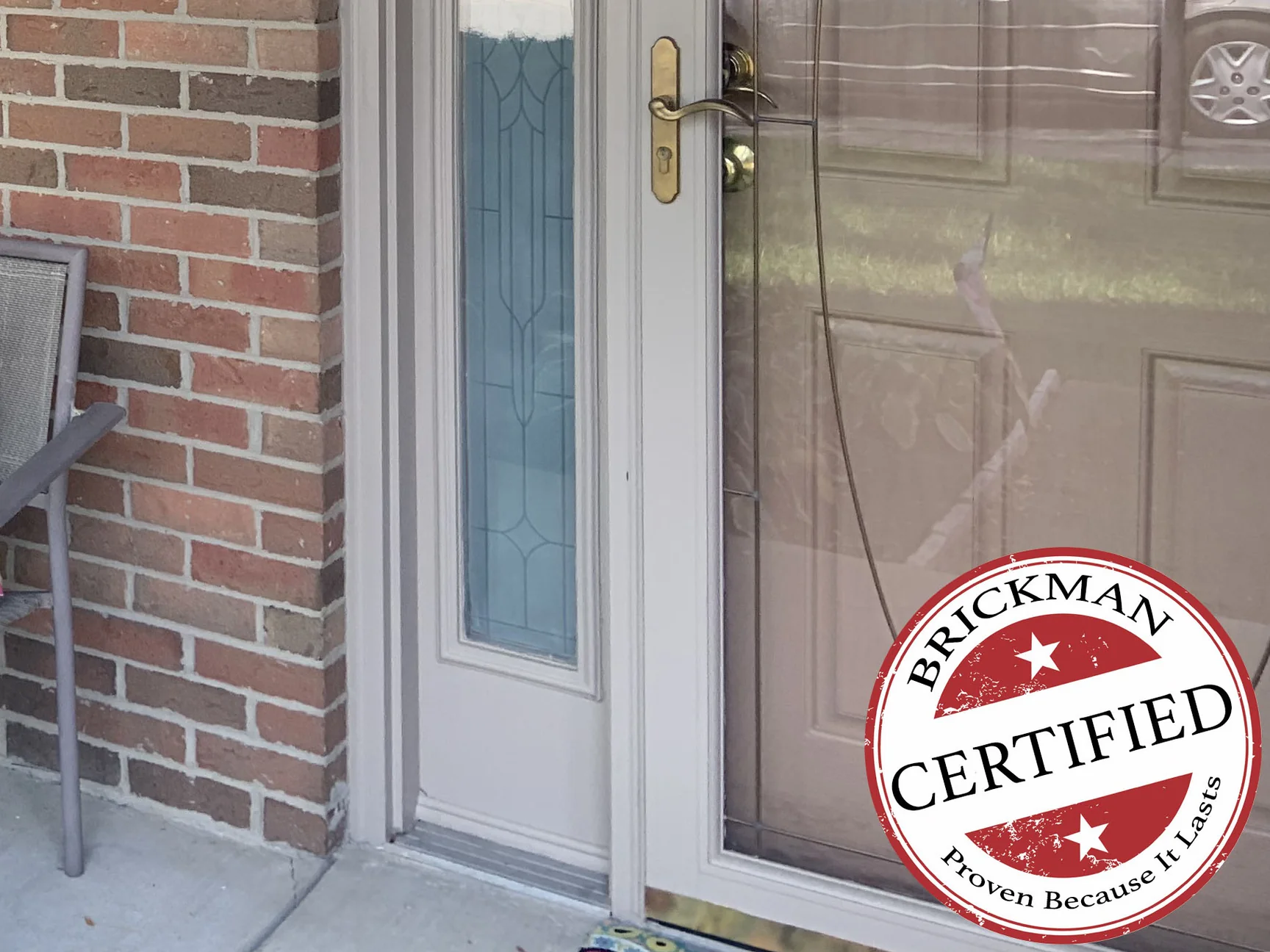 The front door and the brick pier beside it in 2019, with the certification stamp on the storm door glass