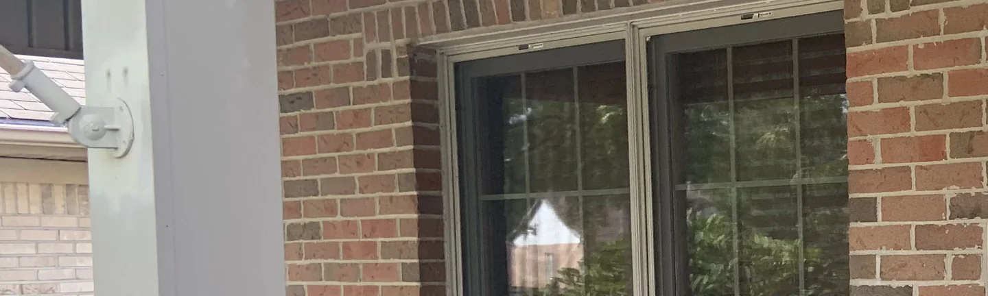 Brick piers and the wall around the front window of an Ohio house in 2019, reading as one even red and brown range