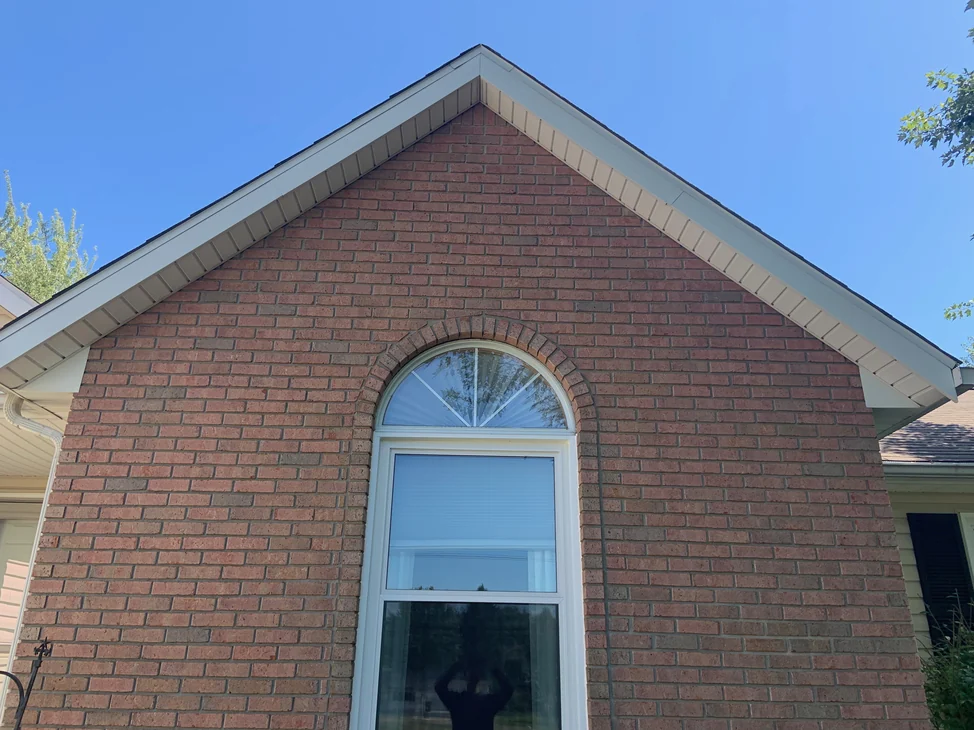 The brick gable end of an Ohio house in 2019, one red and brown range through every course around the arched window.