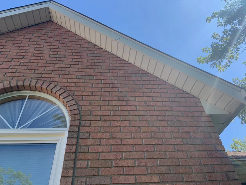 The arched brick header over the window at close range in 2019, the ring of rowlock units and the field around it holding the same range out to the eave