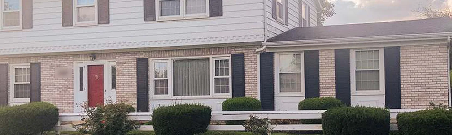 The front of the Ohio house in 2019, the original wall and the addition on the right carrying one cream brick range under white siding