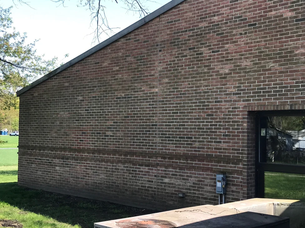 The library's long side wall in 2019, the brick holding one even red and brown range from the ground to the roofline