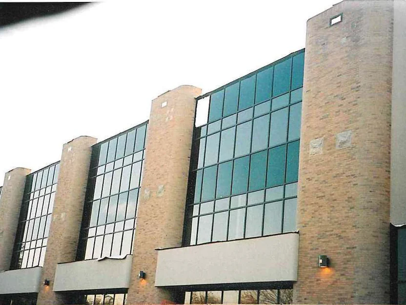 The highway side of the hospital in 2001 before staining, five rounded piers of pale pink brick standing between bays of green glass above a concrete band
