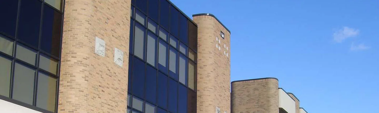 The upper wall of the Ohio hospital in 2019, rounded buff brick piers standing between bays of dark glass under a clear sky