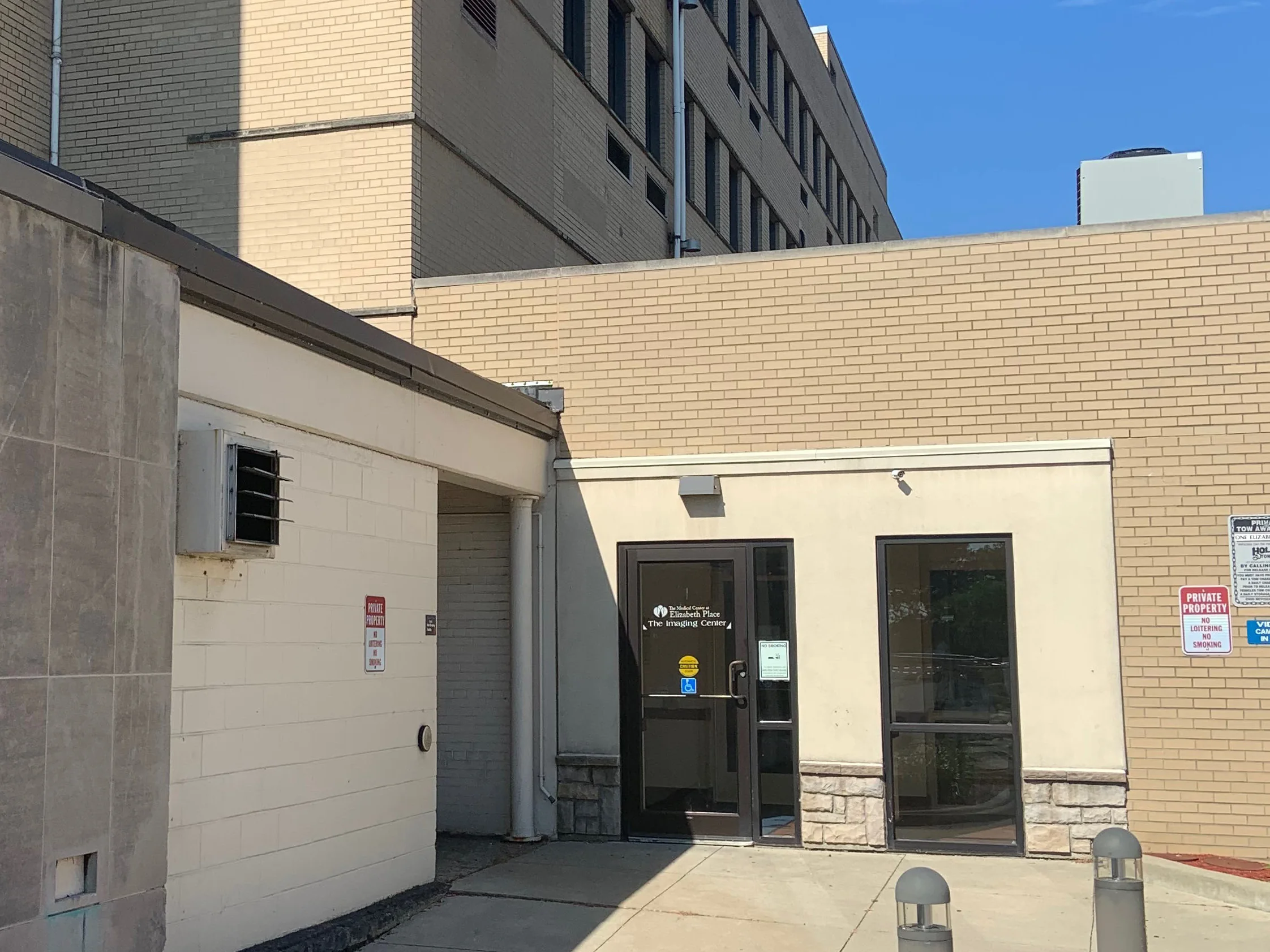 The courtyard entrance of the medical center in 2019, the tan brick of the single-story block and the buff brick of the tower behind it each reading as an even range
