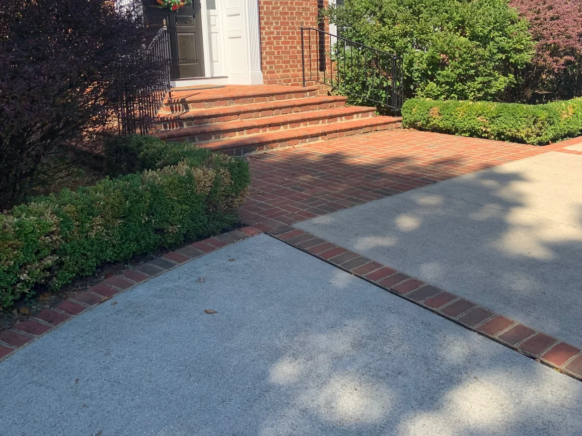 The paver walk seen from the drive in 2019, a brick border running between two concrete slabs and up to the entrance steps