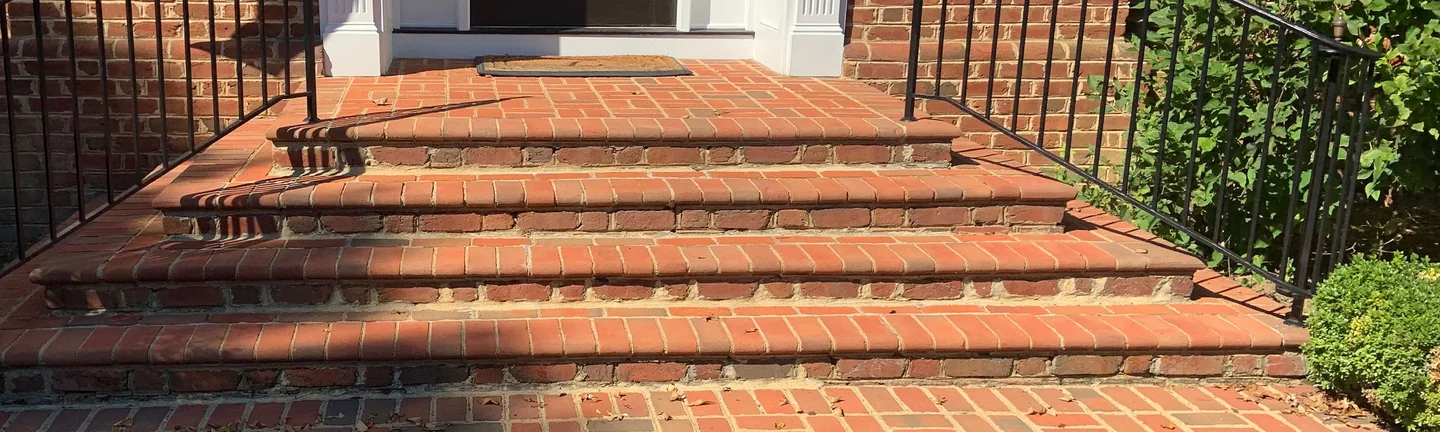 The brick paver steps at the house entrance in 2019, treads and coping reading in the same red range as the pavers around them