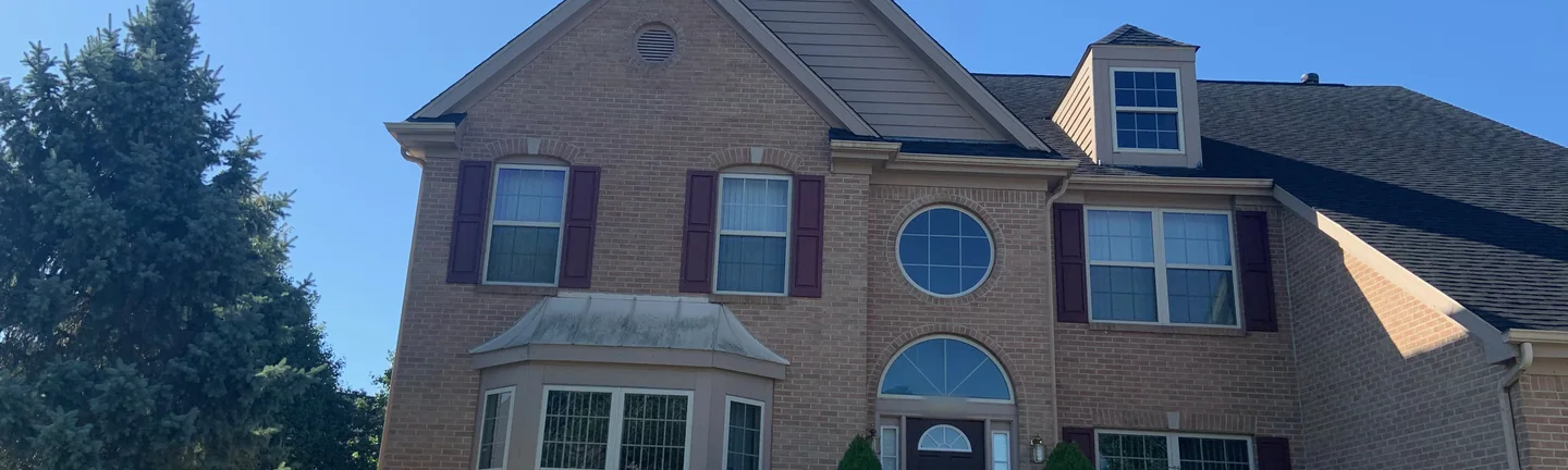 The front of the Ohio house in 2019, brick running as one color across the upper floor, the round window over the entry and the bay below