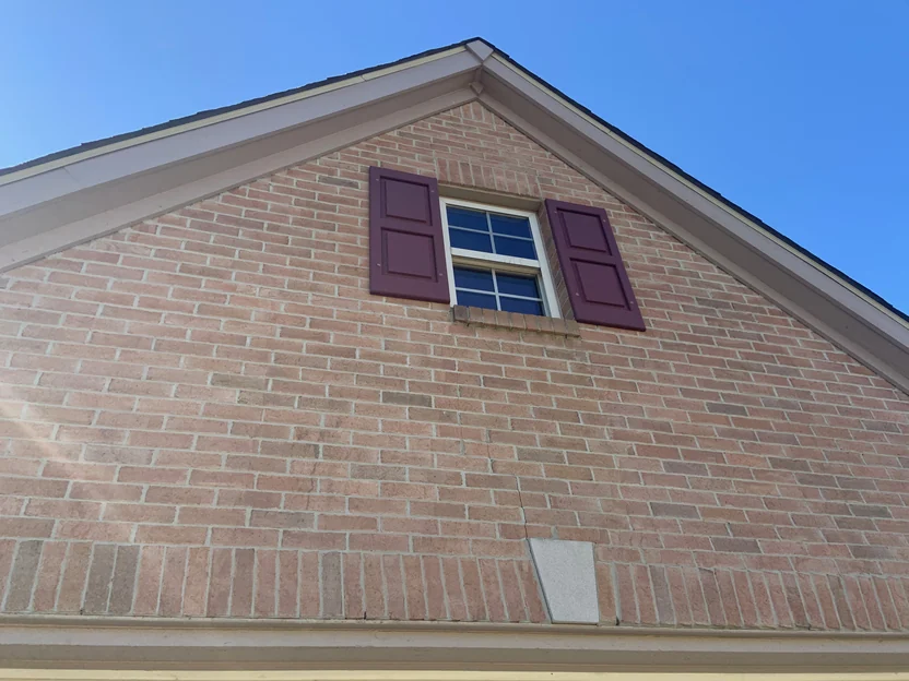 The same gable in 2019, the brick reading as one range from the roof rake down past the shuttered window to the courses below