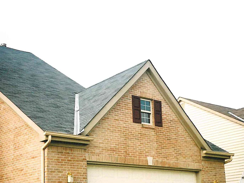 The garage gable in 2002, tan brick around a shuttered gable window with a lantern on the pier below and a ladder standing at the right