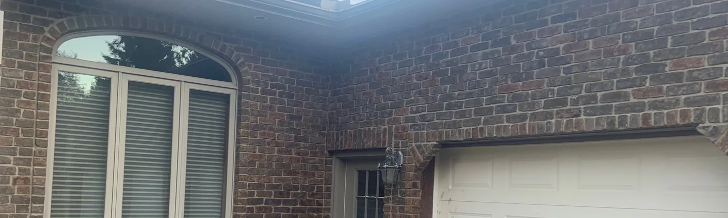 The corner of the Ohio house in 2019, its blended red and brown brick running unbroken round from the arched window to the garage