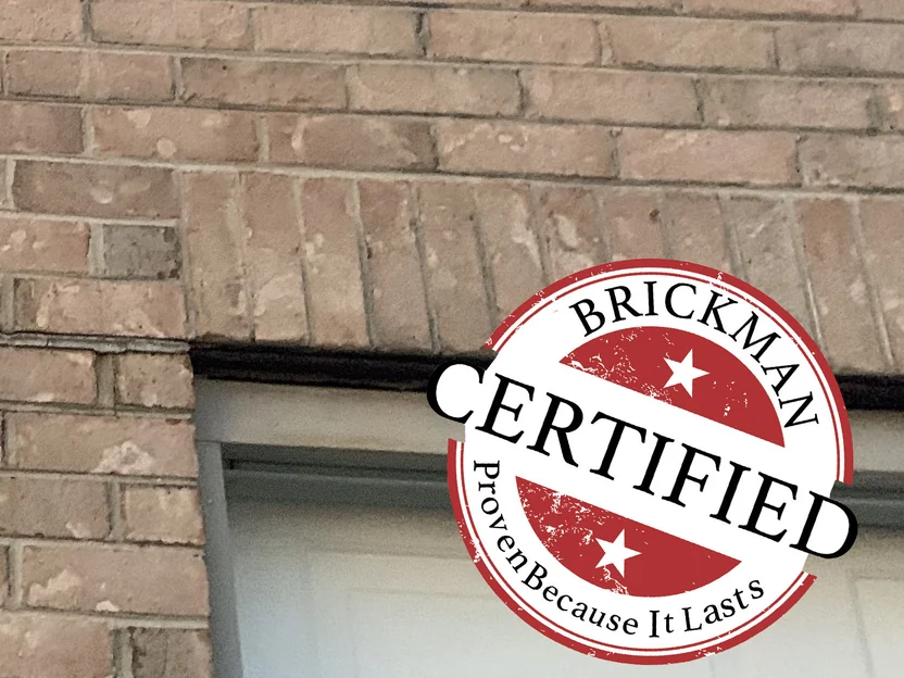 Close view of the brick above the garage opening in 2019, the units reading as one range at arm's length, with the Brickman certification stamp over the corner